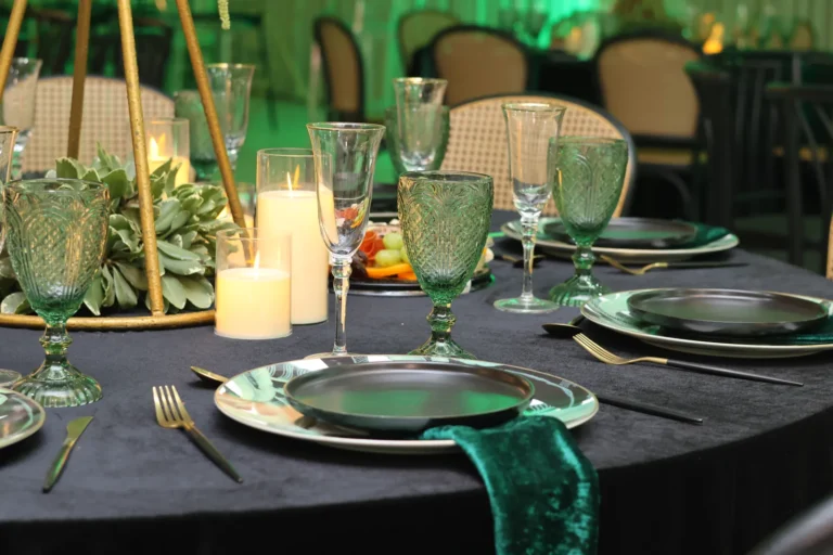 Mesa montada en negro y verde esmeralda con vajilla y copas elegantes