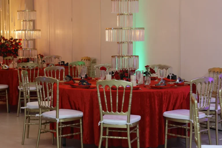Montaje de banquete con mantelería roja y sillas doradas