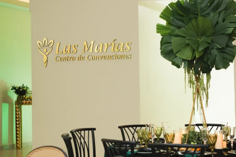 Salón con el logo de Las Marías y centros de mesa de palmas